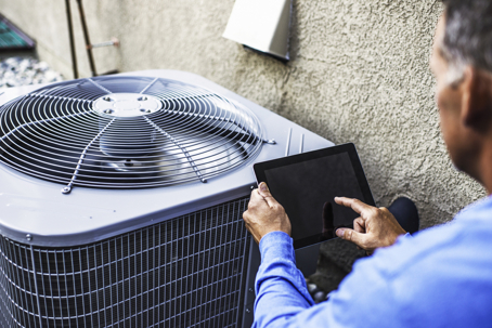 man inspecting an outdoor condenser